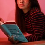 Woman in Striped Long Sleeve Shirt Holding a Book