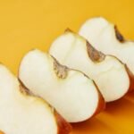 Fresh ripe pieces of apple placed in row on bright yellow background of studio