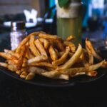 potato fries on black ceramic plate on top of wooden table