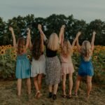 group of girls standing on sunflower field during daytime