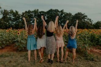 group of girls standing on sunflower field during daytime