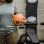 Anonymous black woman with weight ball standing in modern gym