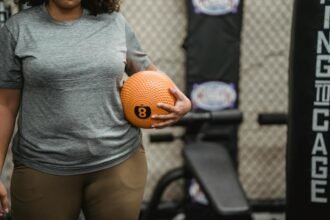 Anonymous black woman with weight ball standing in modern gym