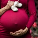 Pregnant Woman Holding baby's shoes