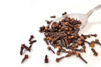 a spoon full of cloves on a white surface