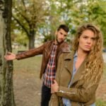 A man and woman in a heated argument outdoors, expressing emotions.