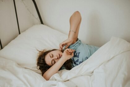 woman covered in white blanket sleeping on white bed comforter